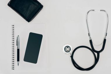 beyaz yüzey üzerinde sağlık stetoskop, defter ve smartphone Üstten Görünüm