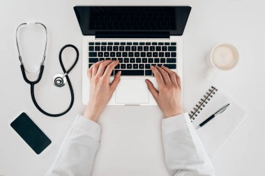 bir dizüstü bilgisayar, stetoskop ve kahve işyerinde doktor kısmi görünümü