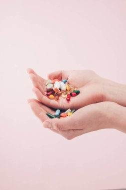 Kısmi görünümünü hapları pembe üzerinde izole elinde tutan kadın