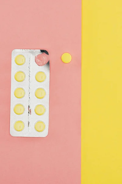 ピンクと黄色の背景で隔離の丸薬の平面図 — ストック写真