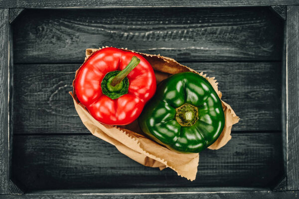 top view of red and green bell peppers in shopping paper bag