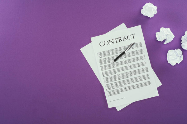 top view of business contract with pen on purple surface