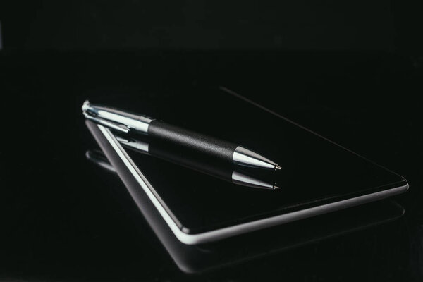 close-up shot of digital tablet with pen on black surface