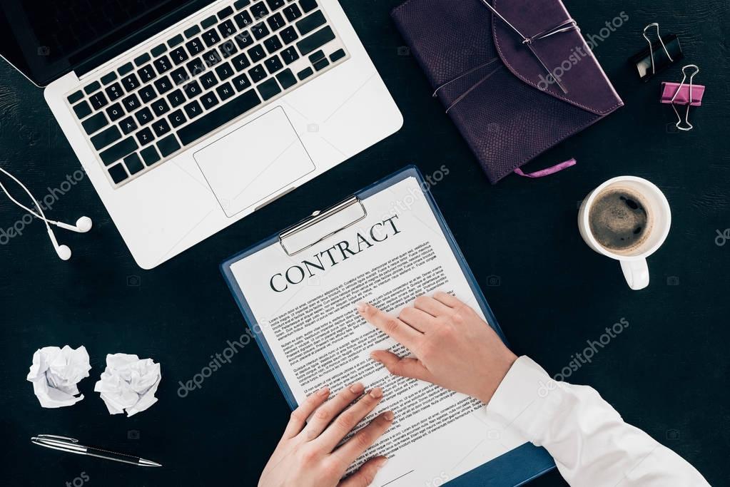 cropped shot of businesswoman reading contract at workplace isolated on black