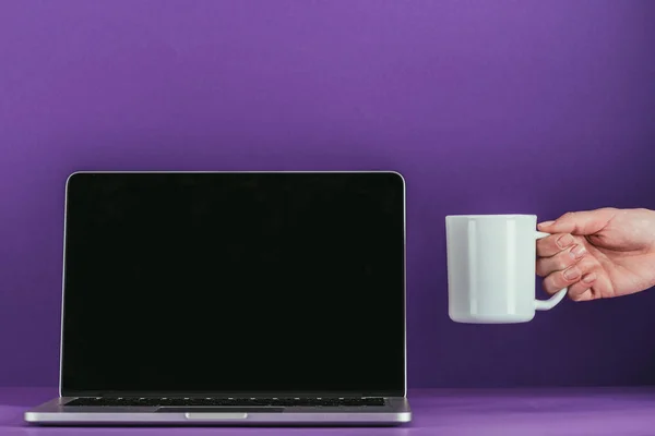 在紫色的表面上的笔记本电脑附近的妇女戈尔丁杯咖啡的拍摄 — 免费的图库照片