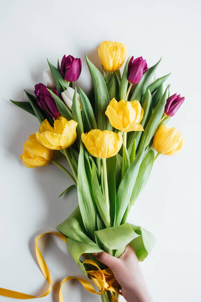 обрезанный вид лица, держащего букет весенних тюльпанов на международный женский день
