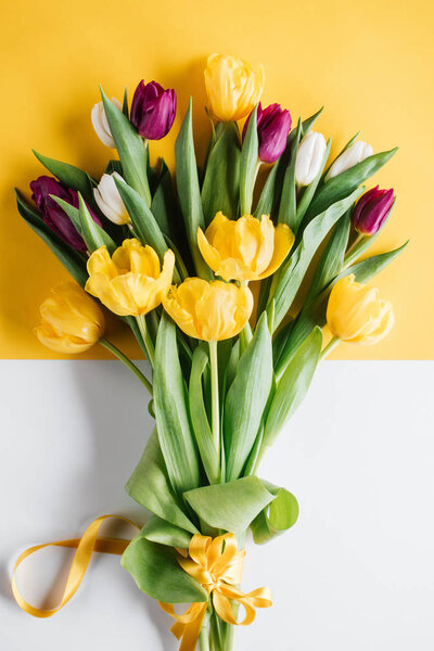 верхний вид желтых, розовых и белых тюльпанов с лентой на международный женский день
