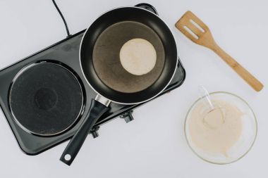 cropped shot of pancake cooking on frying pan and dough in bowl on grey clipart