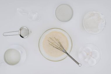 Üstten Görünüm hamur ve çırpma teli, malzemeler ve yemek pişirmek için mutfak eşyaları üzerinde izole gri krep