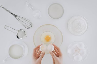 cropped shot of person holding eggshell while cooking pancakes isolated on grey clipart