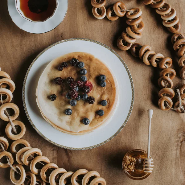 Ovanifrån Söta Läckra Pannkakor Med Bär Kopp Honung Och Bagels — Gratis stockfoto