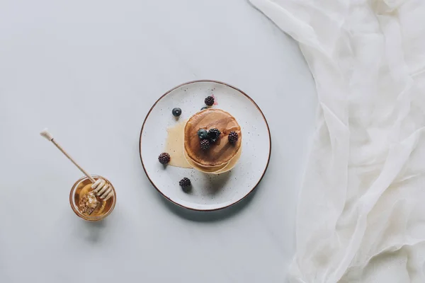 在灰色的蜂蜜和浆果美味自制煎饼的顶部视图 — 图库照片