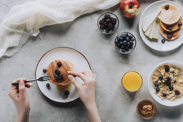 cropped shot of person eating delicious homemade pancakes with berries for breakfast