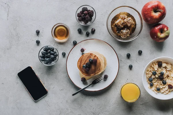 top view of smartphone with blank screen and tasty healthy breakfast on grey