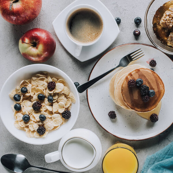 top view of tasty healthy breakfast with pancakes, fruits and muesli on grey 