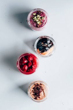 top view of various sweet tasty desserts in glass jars on white clipart