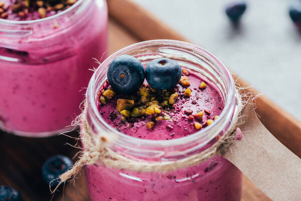 close-up view of sweet healthy smoothie with granola, nuts and berries  