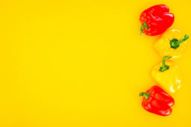 top view of fresh raw organic peppers isolated on yellow clipart