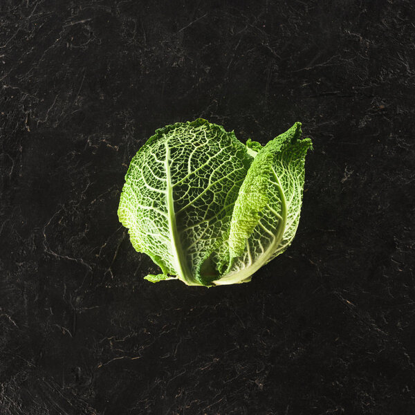 top view of fresh healthy organic savoy cabbage on black  