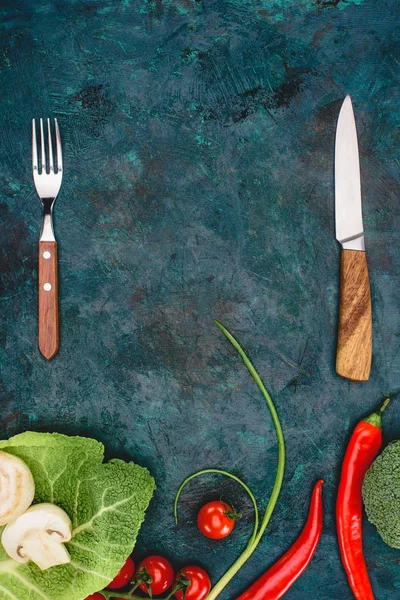 top view of fork with knife and fresh healthy vegetables on black
