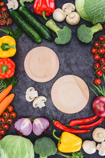 Top view of empty wooden plates and fresh raw vegetables on black — Stock Image Top View Empty Wooden Plates Fresh Raw Vegetables Black Stock Photo