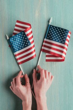Amerikan bayrakları tutan kadın kısmi görünümünü mavi ahşap masa, Başkanlar Günü kavramı üzerinde eller