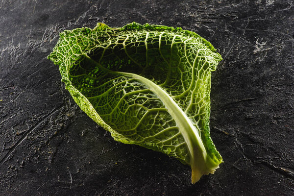 close-up view of leaf of fresh healthy savoy cabbage on black  