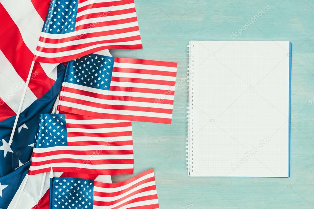 top view of arranged american flags and blank notebook on blue wooden tabletop, presidents day concept
