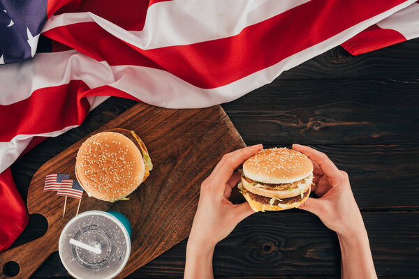 partial view of woman holding burger, presidents day celebration concept