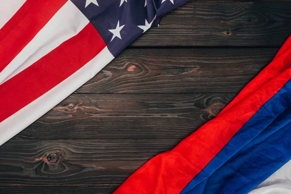 top view of american and russian flags on dark wooden tabletop