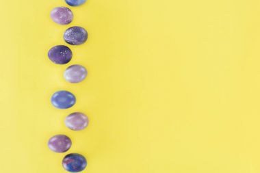 top view of purple painted easter eggs, isolated on yellow background