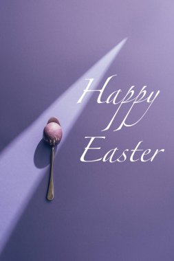 Mutlu Paskalya yazı mor zemin üzerine kaşık boyalı yumurta