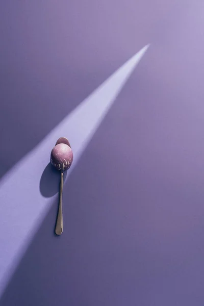 Пасхальное Окрашенное Яйцо Ложку Фиолетовом Фоне Солнечным Лучом — стоковое фото