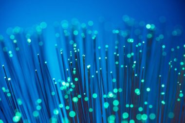 Close up of shiny green fiber optics on blue texture background clipart