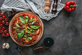 pohled shora čerstvě upečené pizzy s frézou a ingredience na betonový stůl