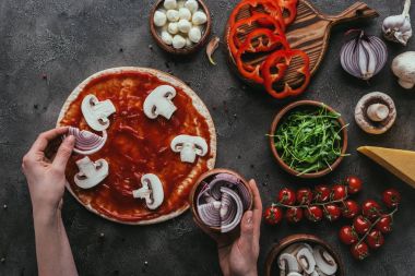 soğan dilimleri üzerine pizza beton tablo üzerinde yayılan kadın görüntüsünü kırpılmış