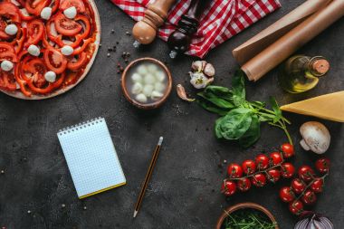 Beton tablosundaki defter ile pişmemiş pizza Üstten Görünüm