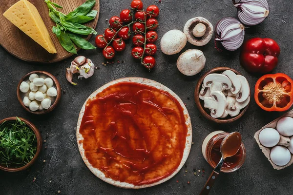 Bovenaanzicht Van Ongekookt Pizza Deeg Met Saus Groenten Betonnen Tafel — Stockfoto