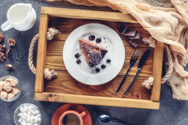 top view of appetizing piece of chocolate cake on plate on wooden tray clipart