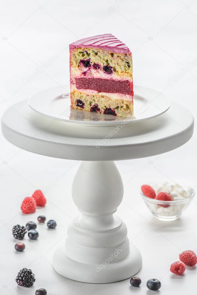 piece of cake with berries on white cake stand