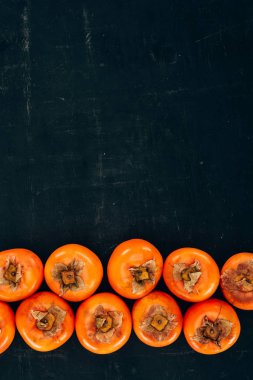 Olgun lezzetli persimmons satırlarının üstten görünüm siyah