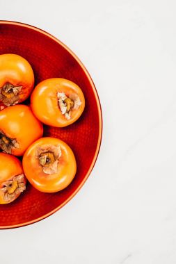top view of persimmons on red plate isolated on white clipart