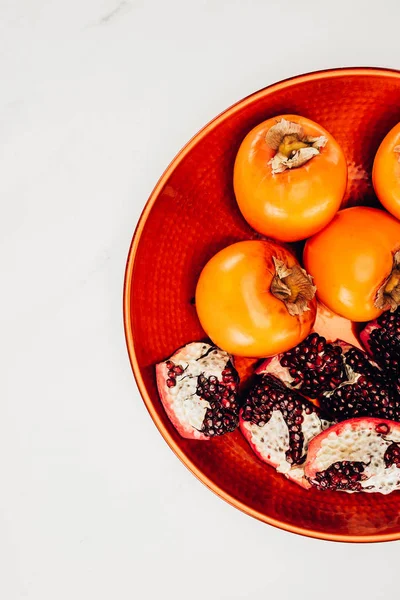 白で隔離赤い皿に柿と石榴のトップ ビュー — ストック写真