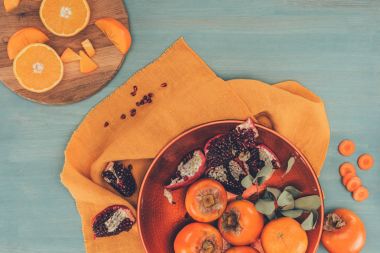 hurma portakal ve nar ile üstten görünüm plaka üzerinde turuncu masa örtüsü