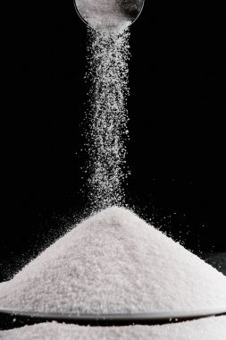 metal kaşık kazık üzerine siyah izole plaka üzerinde düşüyor şeker