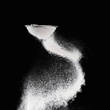 sieve with falling flour isolated on black clipart