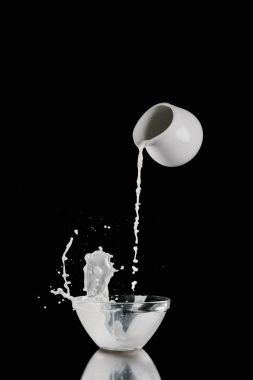 milk pouring from milk jar into bowl on black clipart