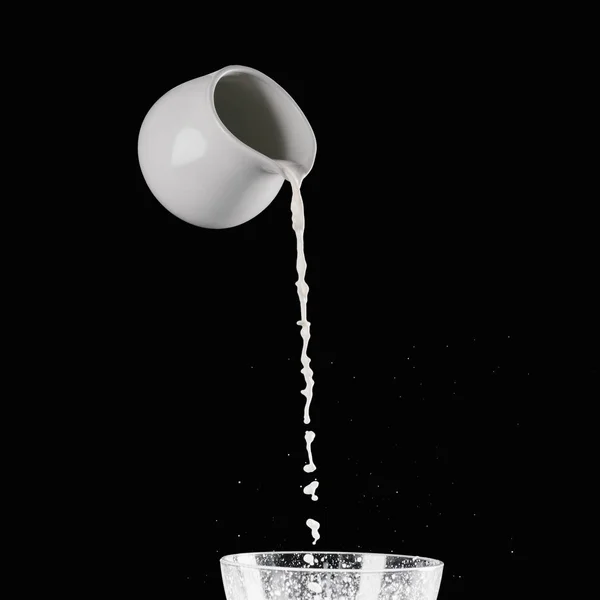 milk pouring from milk jar into bowl with flour isolated on black