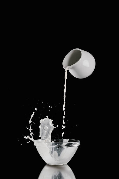 молоко, наливаемое из банки молока в миску на черный
