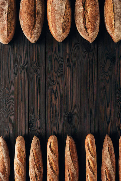 top view of arranged loafs of bread and french baguettes on wooden surface